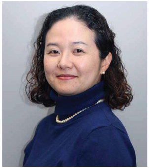 A smiling woman wearing a dark blue turtle neck 